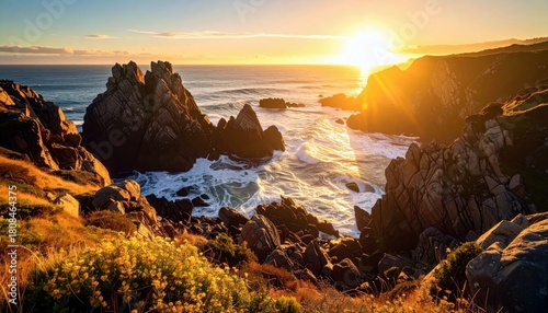 A breathtaking sunset casts a warm golden glow over a rugged coastline, with waves crashing against jagged rocks and vegetation.