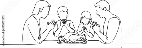 Family praying before a roasted turkey dinner meal