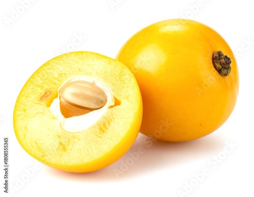 Ripe nance fruit halved showing seed on white surface