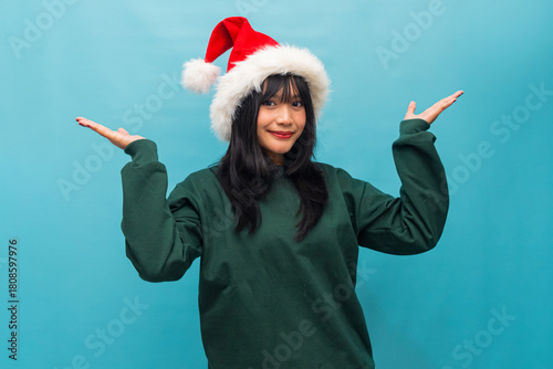 Smiling Asian woman raises her palms expressing curiosity Ideal for Christmas themed ads and lifestyle visuals
