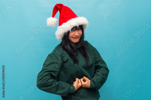 Confident woman in Santa hat poses with a fun flex gesture Ideal for Christmas strength and empowerment themed visuals