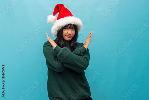 Cheerful woman in Santa hat makes an X gesture with arms Ideal for Christmas themed messages and creative campaigns