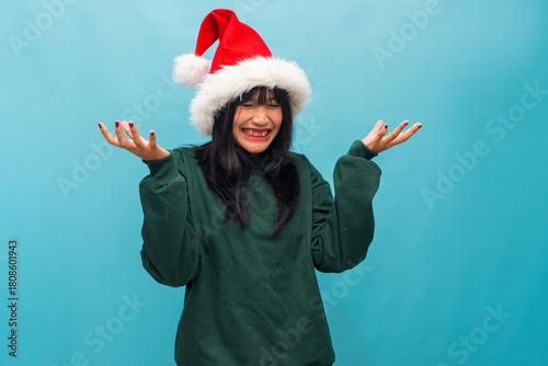 Joyful woman in Santa hat raises hands smiling happily Ideal for Christmas greetings and festive lifestyle promotions