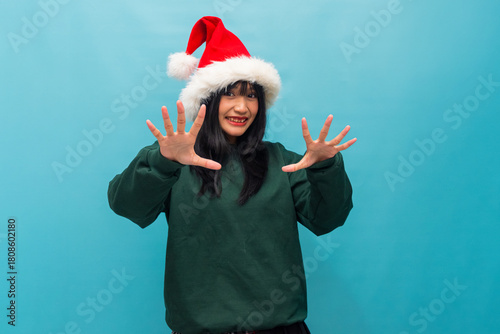 Smiling woman in Santa hat spreads hands forward showing excitement Ideal for Christmas joy and holiday promotions