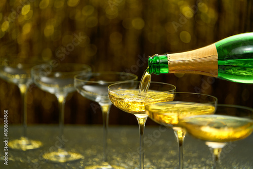 pouring champagne wine from bottle in a coupe glasses, selective focus. champagne poured in a champagne glases.