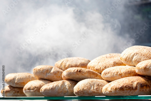 Fototapeta Naklejka Na Ścianę i Meble -  View of breads in the street shop. Small loaves, rolls. Smoke from the grill in the background.