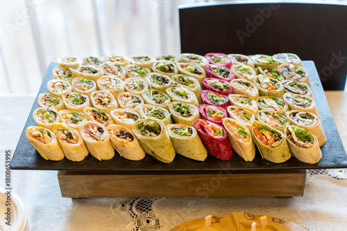 Colorful platter of assorted wraps ready for a buffet at a gathering in a bright indoor setting