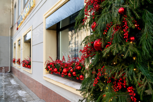 Christmas street decorations: a shop window decorated with fir branches, red balls and berries