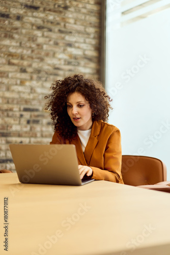 Professional Woman Working On Laptop At Modern Office With Brick Wall Backdrop For Remote Work
