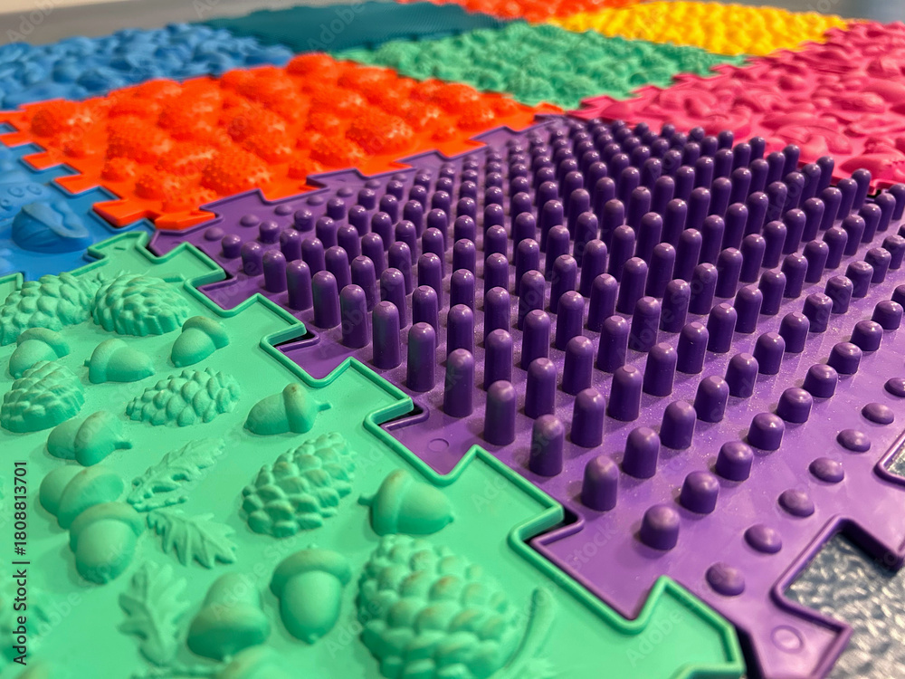 Obraz premium Colorful textured sensory floor tiles arranged in a close-up pattern highlighting diverse shapes and raised surfaces