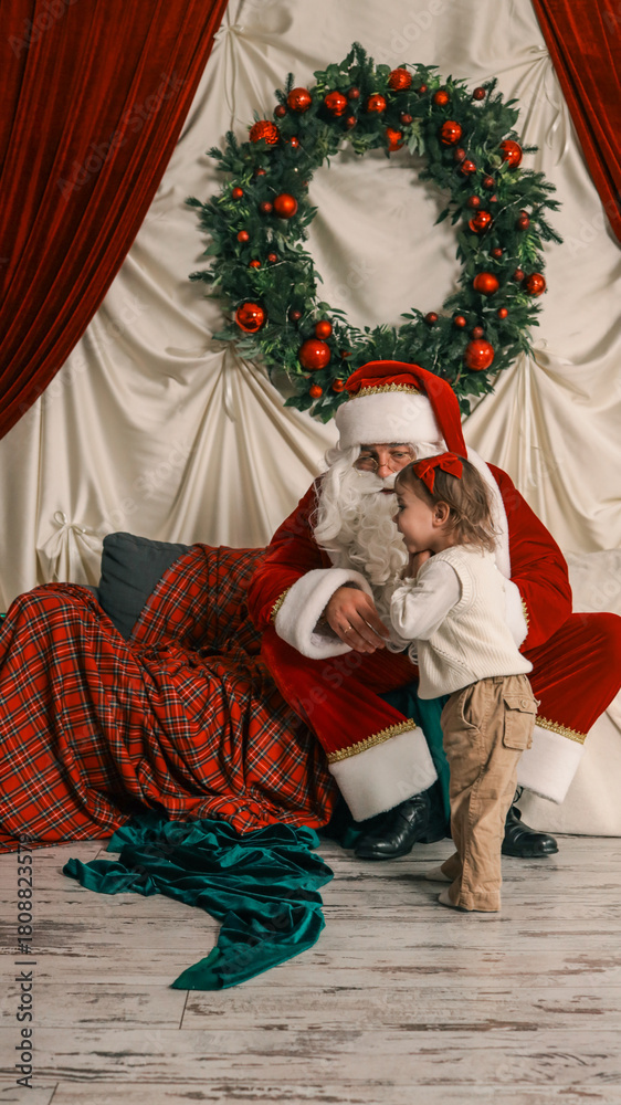 Naklejka premium Santa Claus with a little girl during a Christmas photoshoot