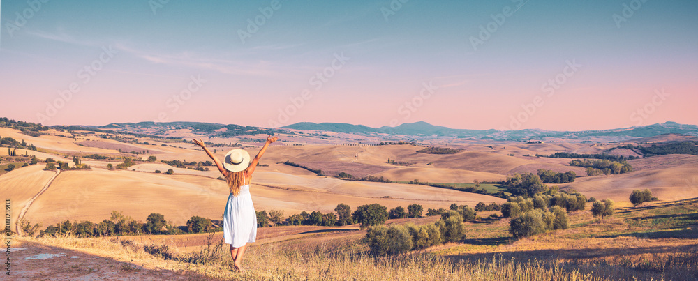 Obraz premium Happy girl in white dress and hat enjoying field in Italian Tuscany at sunset