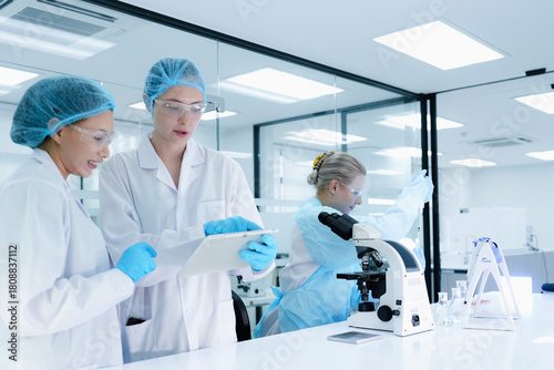 Fotografía A senior scientist mentors a junior colleague in a modern lab, using a tablet to guide her through a precise pipetting technique, fostering hands-on learning and skill development