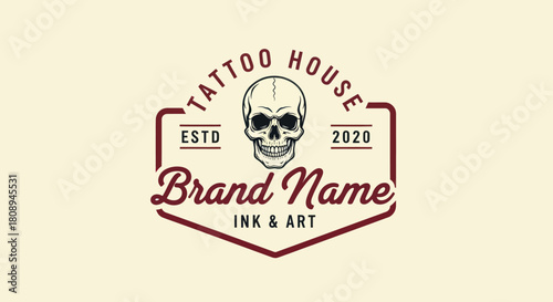 Vintage tattoo studio logo featuring a detailed human skull emblem within a classic badge design.