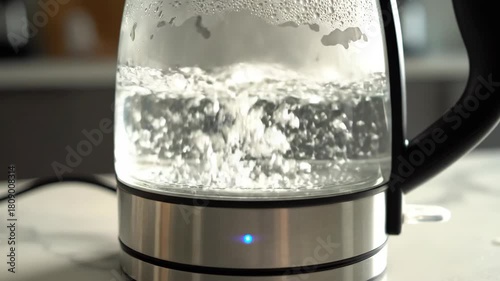 Glass electric water kettle heating clear liquid with visible bubbles rising