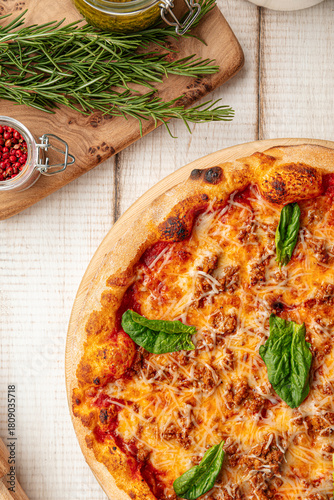 Hot fresh baked pizza topped with melted cheese tomato sauce minced meat and basil leaves on board