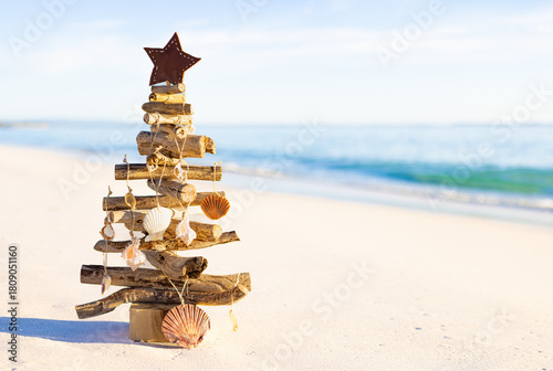 Sea shells decorate rustic wooden Christmas Tree on the beach