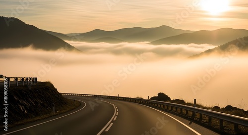 Winding road leading to mountains covered in fog during a bright sunny day in the countryside