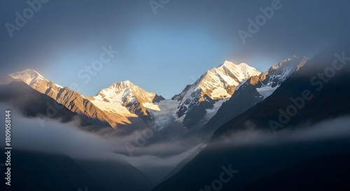 Snow capped mountains rise majestically above a sea of clouds under a clear blue sky at sunset