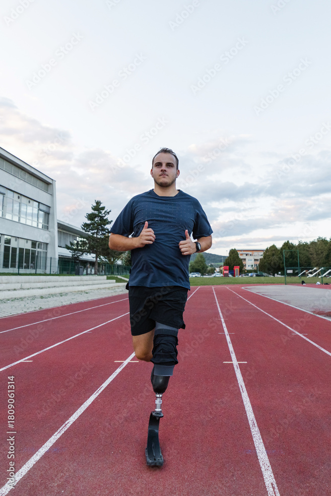 Obraz premium Man with a disability running on the athletic track wearing a prosthetic leg, blade with a heel plate designed for sports activities.