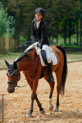 Fotografie Equestrian sport, young woman riding a horse in outdoor arena, horsewoman in competition, dressage, horseback riding, training, equine activity, outdoor lifestyle