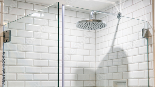 Modern shower cabin with glass doors and white subway tile wall creating a clean and minimalist bathroom