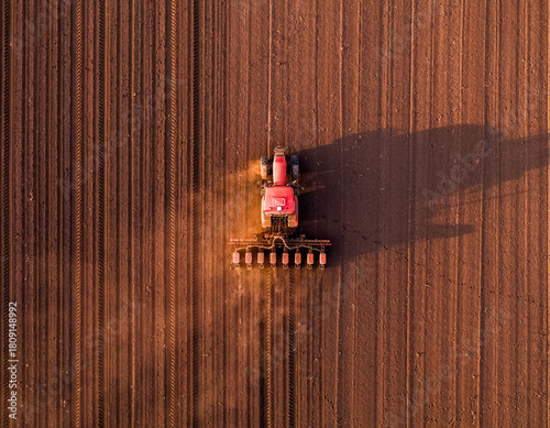 Farming tractor sowing seeds on cultivated agricultural field