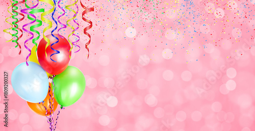Colorful balloons on pink blurred background with confetti and streamers for party time. Empty space for text