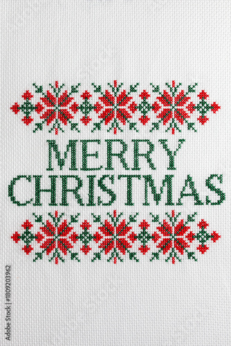 Merry Christmas is embroidered with green thread on white fabric. 