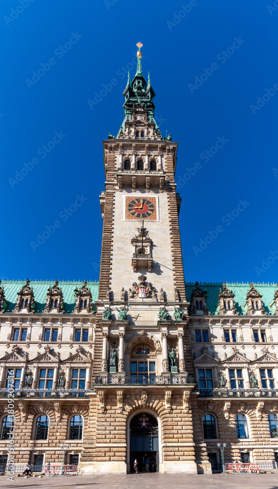 Fototapeta premium The impressive clock tower and main entrance of Hamburg City Hall (Rathaus) in Germany, captured on a clear, sunny day against a bright blue sky
