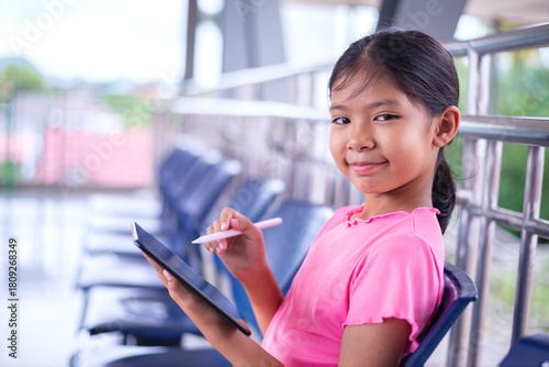 Smiling Young Girl Using Stylus on Digital Tablet