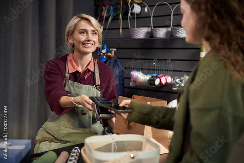 Foto Caucasian middle aged woman wearing apron smiling, while handing payment termina