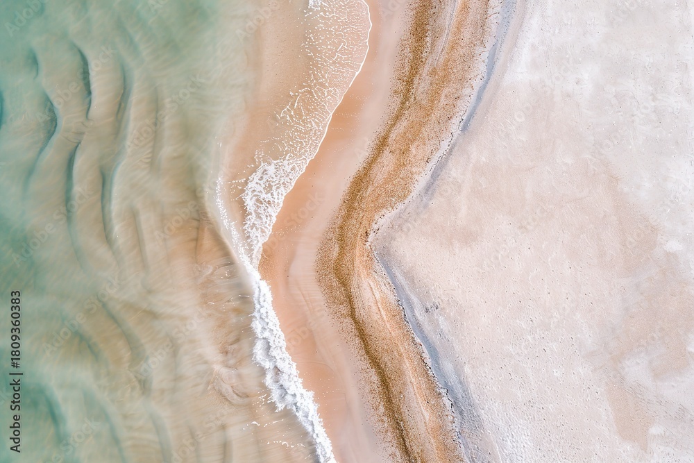 Fototapeta premium This scene reveals a beautiful coastal landscape seen from above, showcasing clear shallow waters meeting sandy shores. Subtle waves gently lap against the beach, revealing intricate patterns