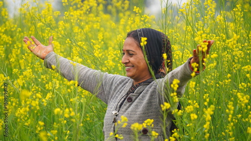 Joyful young woman in the mustard field opening her hands and looking upside in sky. Farmer lady happy to see her growing crops. Winter crops. Rural agriculture concept. Hand pose