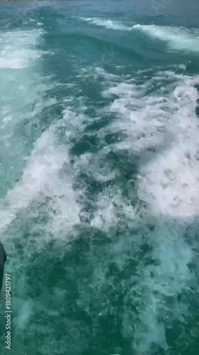A close-up of the churning wake of a tourist boat's engine on emerald water.