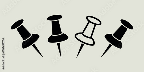 Four black push pins arranged in a scattered pattern