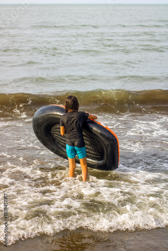 little girl holding a rubber boat on the beach