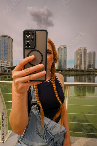 Portrait Of Attractive Young Woman In Black T-shirt Holding Phone Taking Picture In City