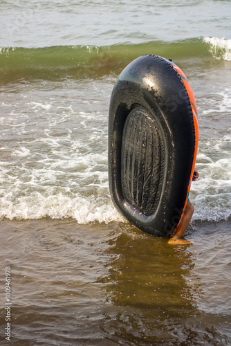 little girl tries to carry a rubber boat on the beach
