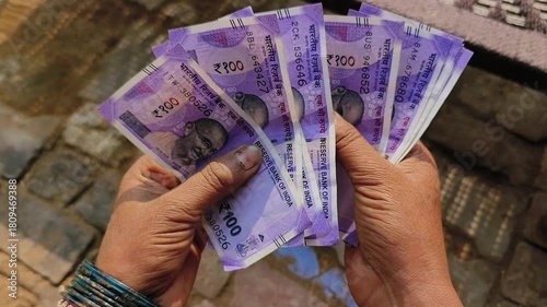 An indian woman counting 100 rupees indian currency notes.