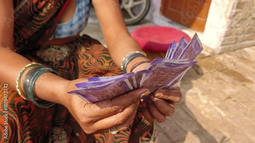An indian woman counting 100 rupees indian currency notes.