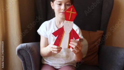 paper craft for kids. child plays with DIY toy Saint Nicholas for sinterklaas day. ball-jointed doll waves its arms