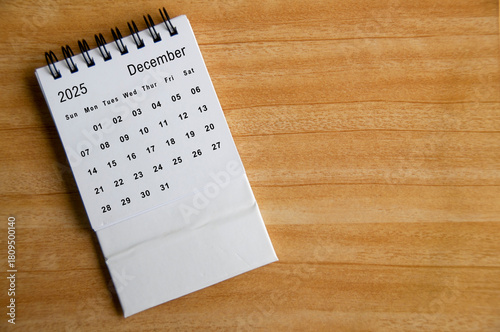 Top view of December 2025 calendar on wooden table. Year end concept.