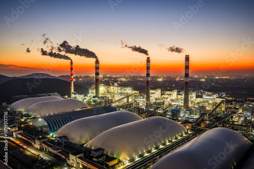 Aerial view of a large thermal power plant with illuminated industrial buildings and smoking chimneys at night