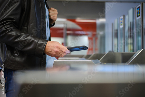 Photography adult male paying using smartphone at subway turnstile