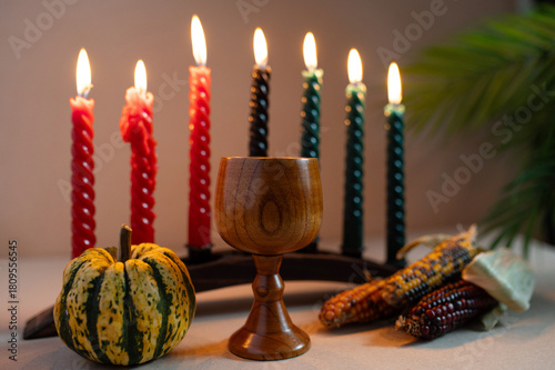 Happy Kwanzaa. Seven candles red, black and green on a natural wooden background. Harvest and gifts. Symbols of African heritage.
