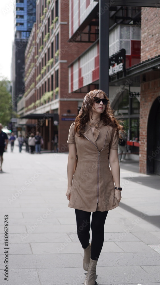 Fototapeta premium Stylish woman walking in the city wearing sunglasses and beige outfit