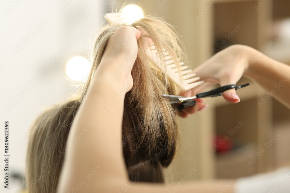 Fototapeta premium Hairdresser cutting woman's hair in salon, closeup