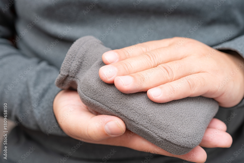 Fototapeta premium man putting hands on a small hot water bag