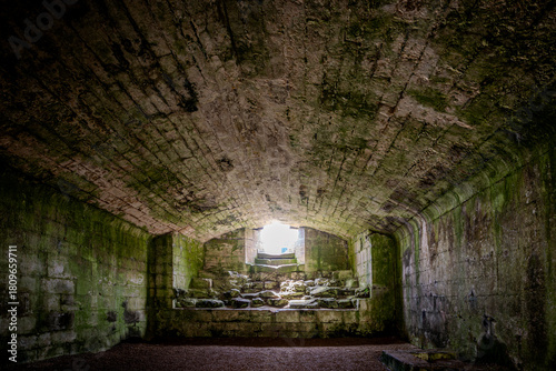 Ancient castle underground cellar of warkworth castle,, Northumberland. UK. Stone walls and cold, damp floor.